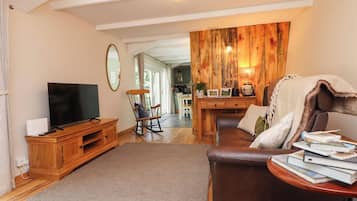 Una sala de estar con televisión, muebles de madera, una mecedora y un comedor con pared de madera.