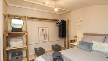 Un dormitorio con cama, lámpara colgante, televisor montado en la pared y un cuadro enmarcado.