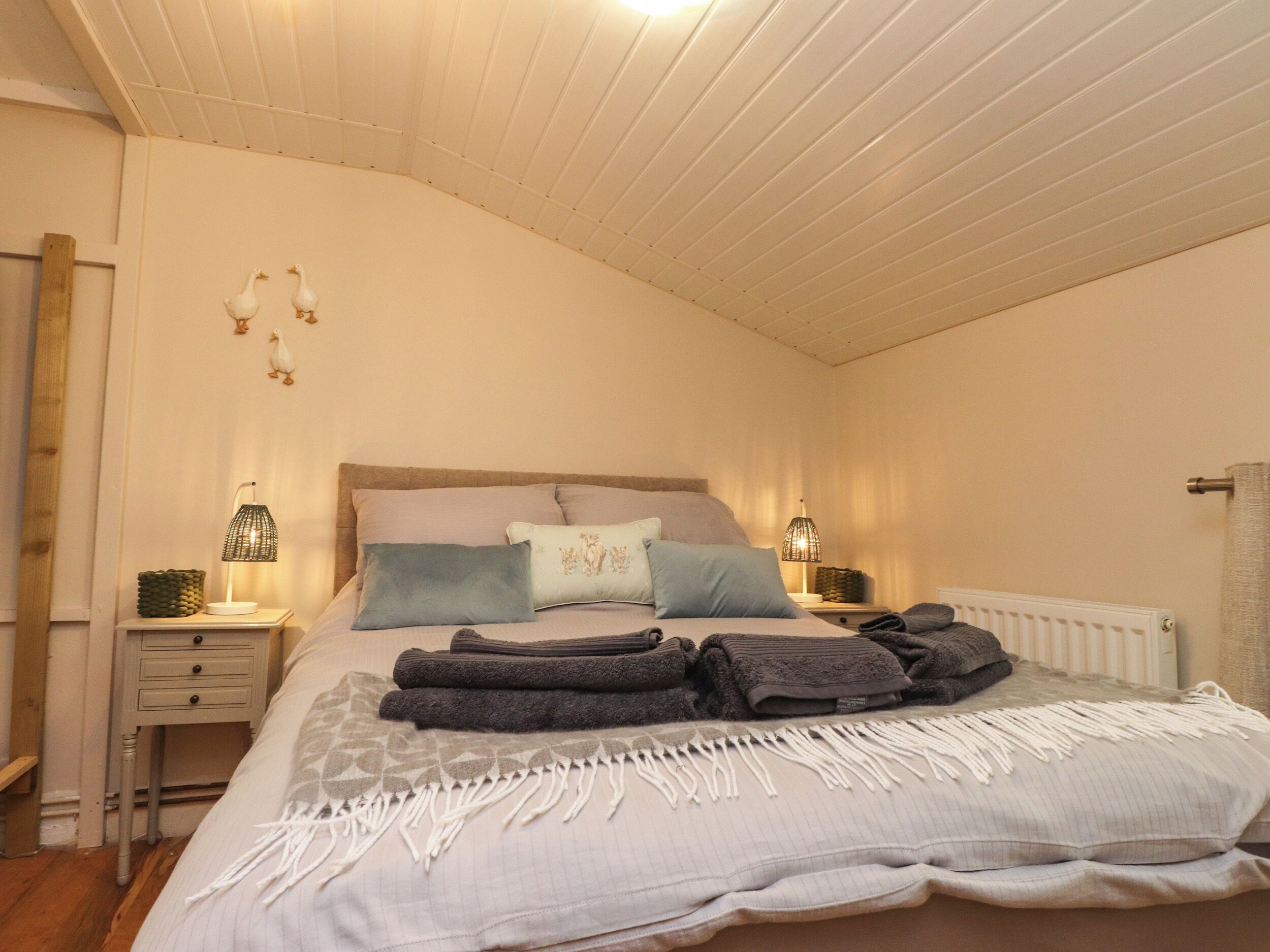 A bedroom with a bed, two bedside tables, a radiator, and wall decorations.