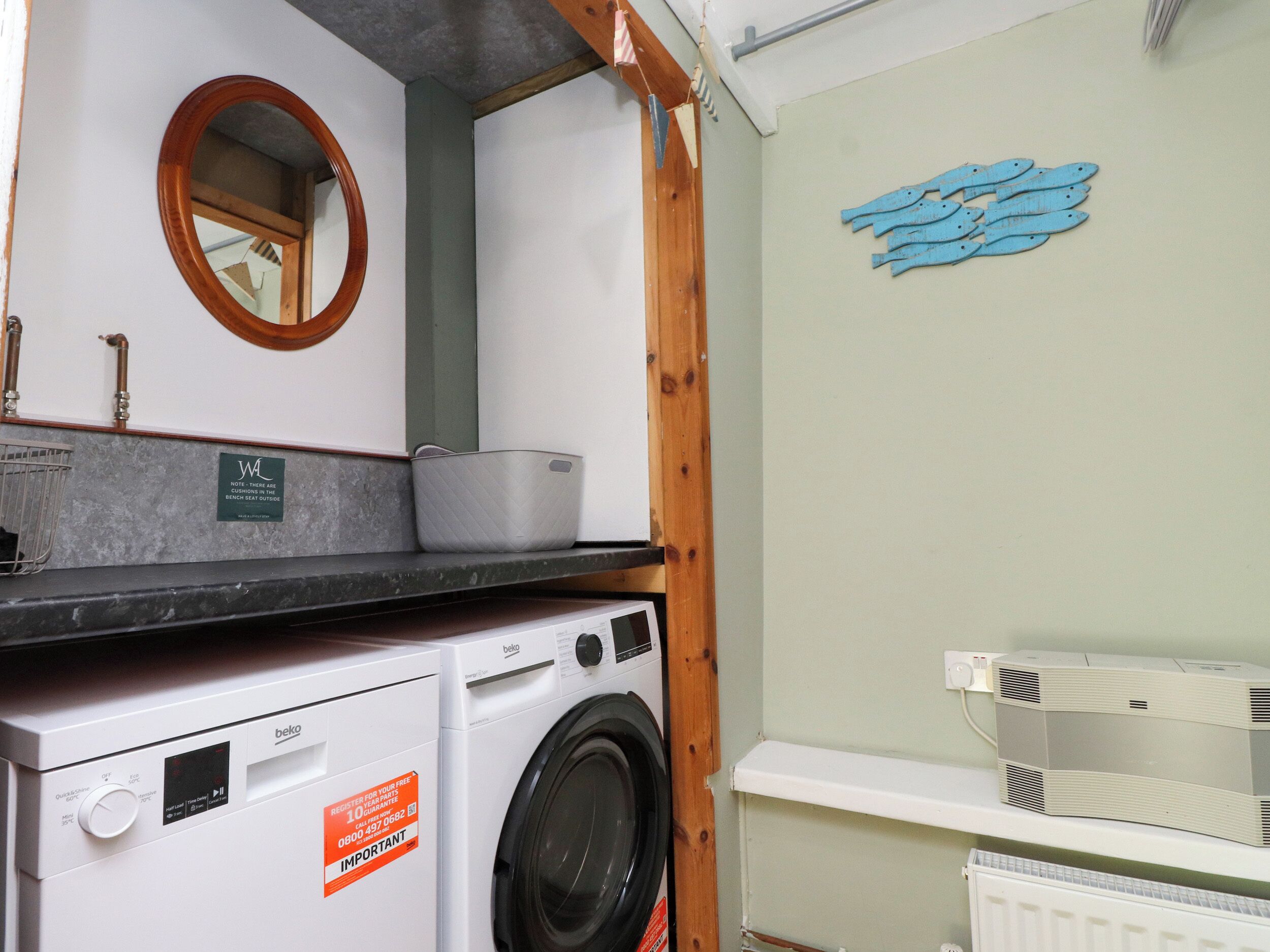 A compact laundry area with a washing machine, a dryer, and a shelf with a radiator.