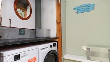 Un lavadero compacto con lavadora, secadora y repisa con radiador.