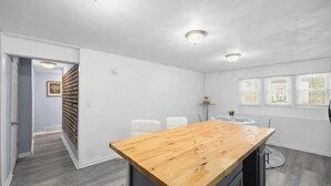 Ein Zimmer mit Holztisch, weißen Wänden und einem Fenster mit Blick.