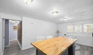 Una habitación con una mesa de madera, paredes blancas y una ventana con vistas.