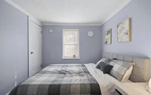 Un dormitorio con cama, ventana y dos relojes en la pared.