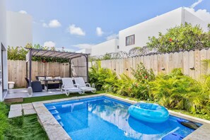 Ein Garten mit Schwimmbecken, überdachter Sitzgelegenheit und Holzzaun.