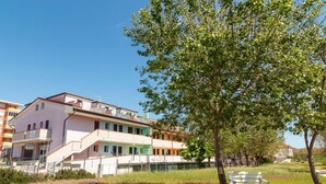 Un immeuble à plusieurs étages doté de balcons, d’une pelouse et d’un banc.