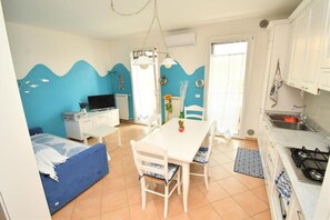 A compact room with a bed, a dining table with chairs, a kitchenette, and a bathroom. - Residenz Arcobaleno, "Granchio" Three-Room Apartment for 6 People (Chioggia)