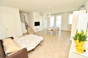 A bedroom with a bed, a desk, and a chair. There is a staircase and a TV mounted on the wall. - Residenz Arcobaleno, Cavalluccio Plus Three-Room Apartment for 6 People (Chioggia)