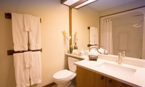 A bathroom with a toilet, sink, mirror, towel rack, and a shower curtain.