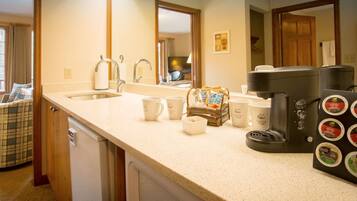 A kitchen with a sink, coffee maker, and coffee pods.