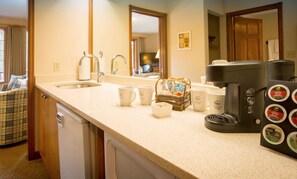 A kitchen with a sink, coffee maker, and coffee pods.