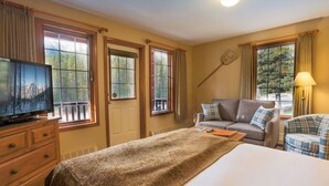 A hotel room with a bed, a television, a sofa, a chair, and windows with curtains. - Lake Louise Escape with Private Deck & Views (Lake Louise)