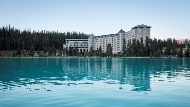 A large, multi-story hotel with a classic architectural style, situated by a calm lake with dense forest in the background. - Lake Louise Escape with Private Deck & Views (Lake Louise)