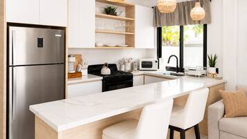 A modern kitchen with a stainless steel refrigerator, a microwave, a stove, and a large island with bar stools.