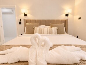 Ein Hotelzimmer mit einem Bett, zwei Wandlampen, einem Kopfteil und einem Paar Handtücher, die auf dem Bett drapiert sind.
