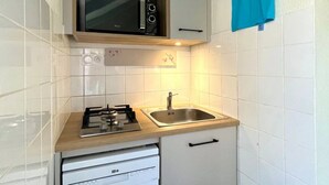 A compact kitchen with a microwave, gas stove, sink, and dishwasher. - Chalet 3 étoiles - Piscine  - eeccga (Arnac)