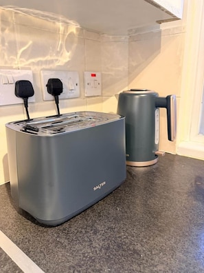 A kitchen with a grey toaster, a kettle, and electrical outlets on the wall. - Apartment Opp Leicester Train Station | Central (Leicester)