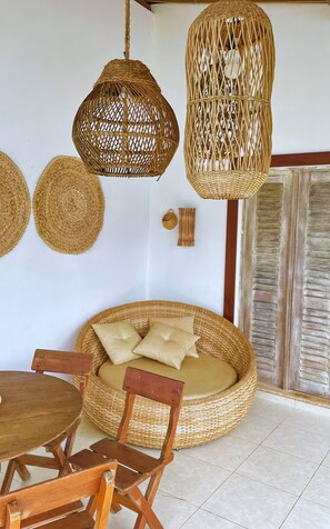 Un sofá de mimbre con cojines, una mesa de comedor de madera y lámparas colgantes de mimbre.