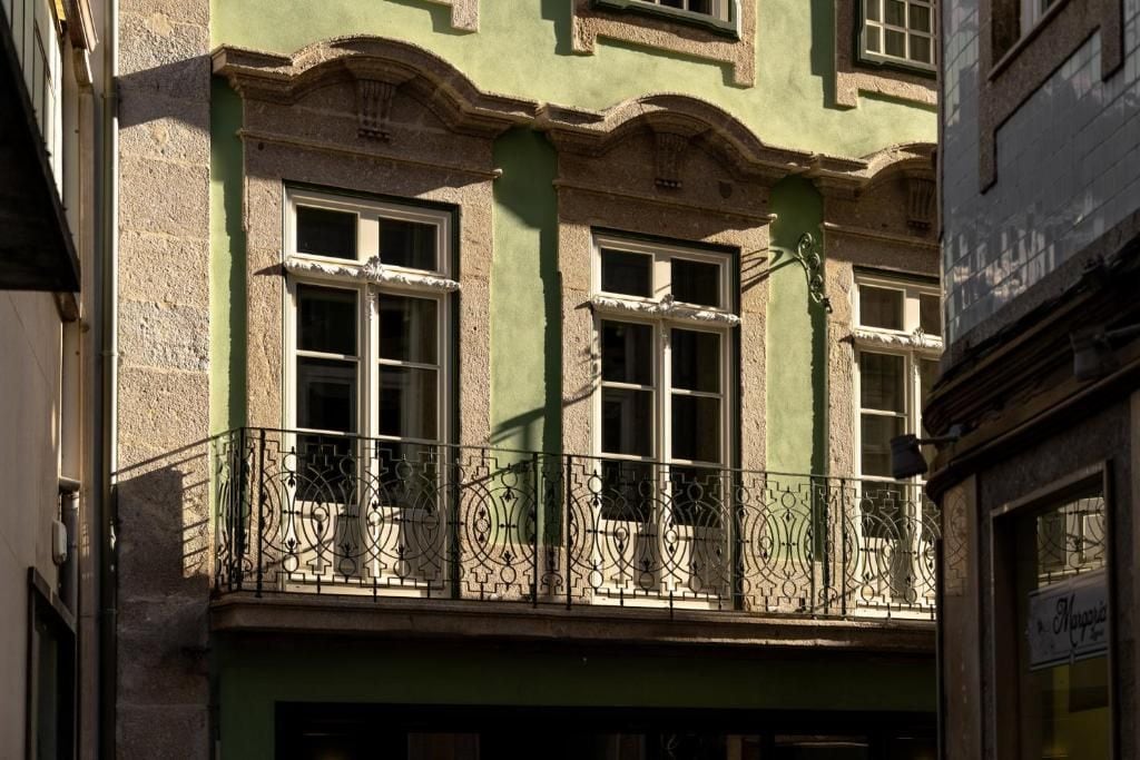 Ein Gebäude mit einem Balkon, der mit aufwendeschmiedeeisernen Geländern und zahlreichen Fenstern versehen ist.
