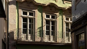 Ein Gebäude mit einem Balkon, der mit aufwendeschmiedeeisernen Geländern und zahlreichen Fenstern versehen ist.