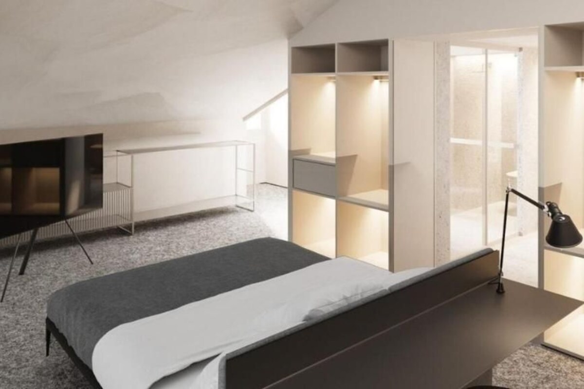 Ein modernes Schlafzimmer mit Bett, Fernseher, Schreibtisch und integrierten Regalen.