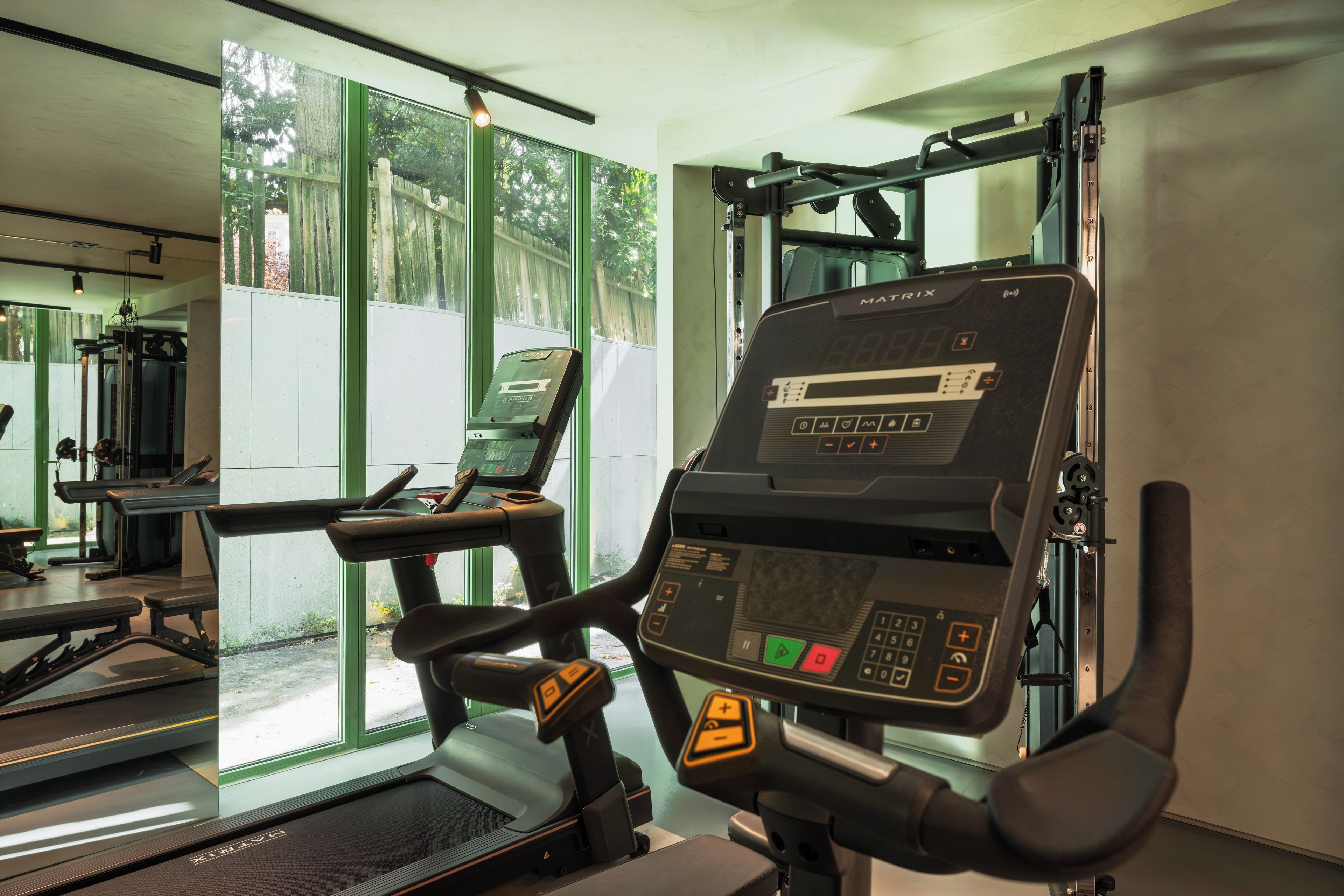 Une salle de sport équipée de matériel d’exercice, notamment un tapis de course et une machine de musculation.