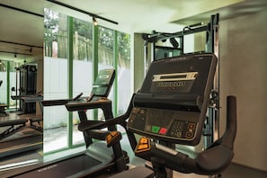 Una palestra con attrezzature per allenamento, tra cui un tapis roulant e una macchina per pesi.