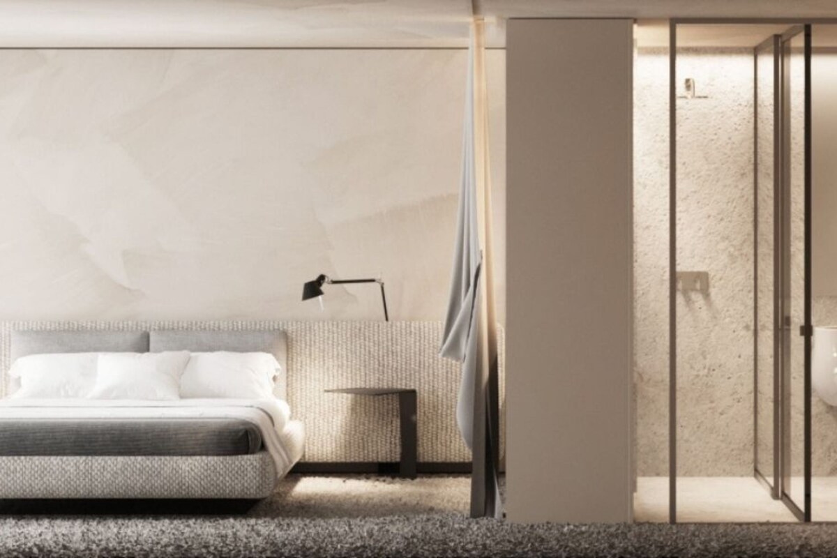 A modern bedroom with a bed, bedside table, lamp, and a glass-enclosed shower area.