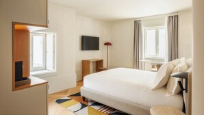 Ein Hotelzimmer mit einem Bett, einem Fernseher, einem Schreibtisch, einem Sessel und einem Fenster.