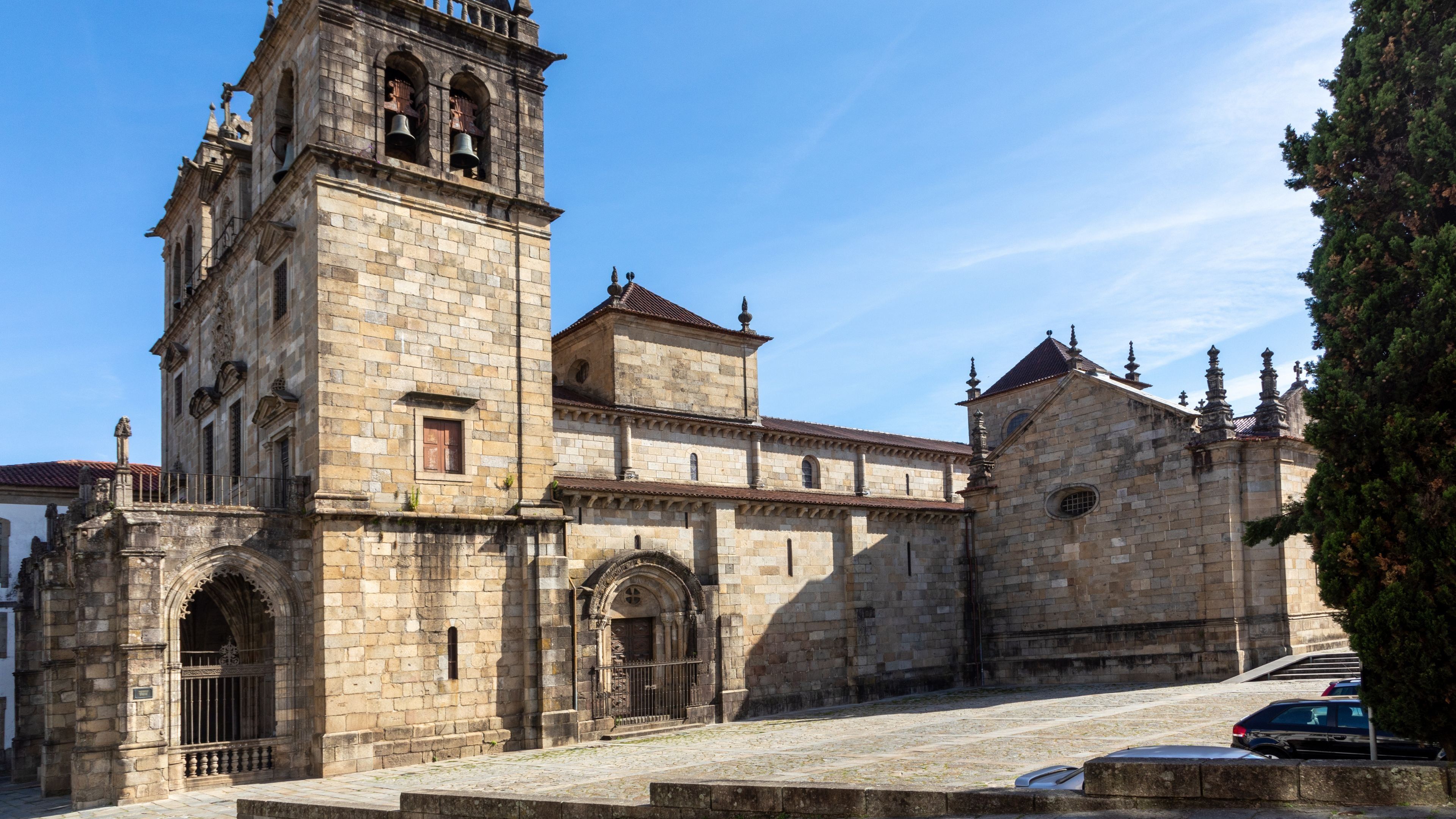 A historic stone building with a bell tower, arched doorways, and a courtyard.