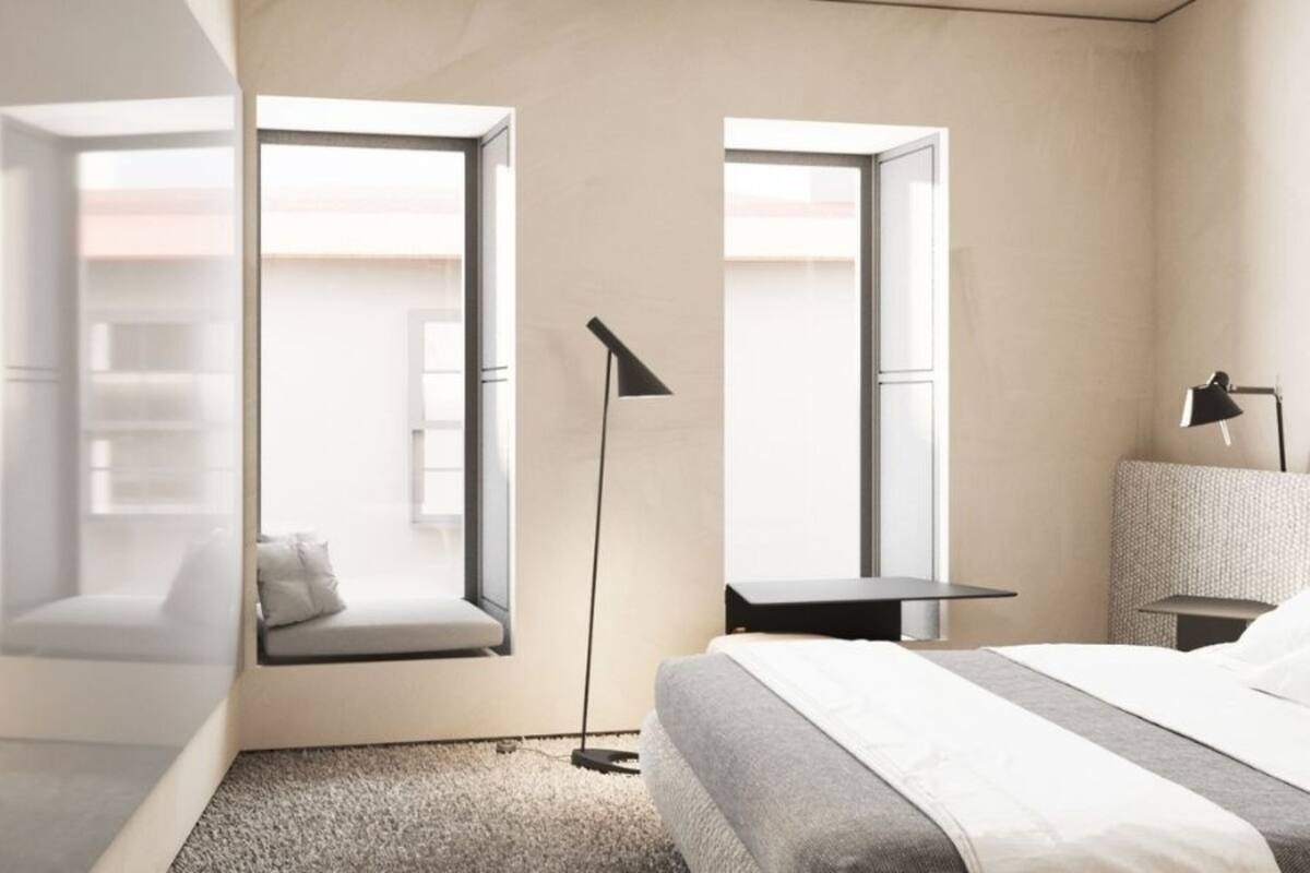 Ein modernes Schlafzimmer mit einem Bett, einem Schreibtisch, einem Stuhl, einer Stehlampe und einem Fenster.
