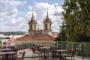 A terrace with outdoor seating, overlooking a historic building with two bell towers.