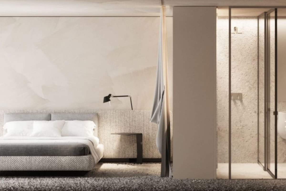 Ein modernes Schlafzimmer mit Bett, Nachttisch, Lampe und einer separaten Duschkabine.