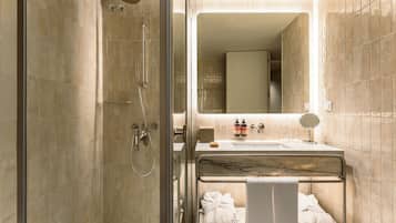 Un baño moderno con ducha envuelta en vidrio, tocador de mármol y espejo.