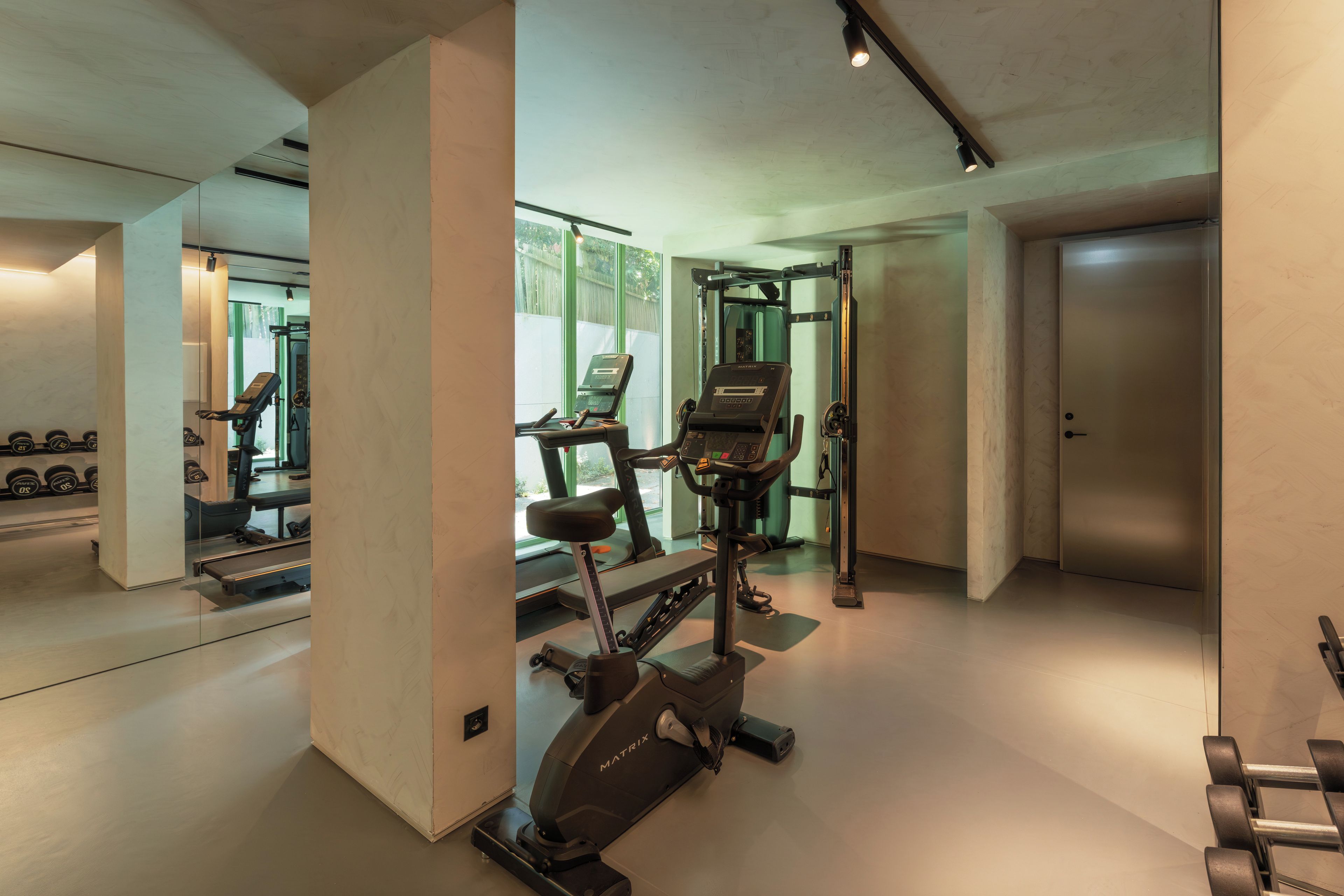 Ein modernes Fitnessstudio mit Laufbändern, Hanteln und einer Spiegelwand.