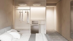 A bedroom with a bed, a built-in wardrobe with hanging clothes, and a bedside table.