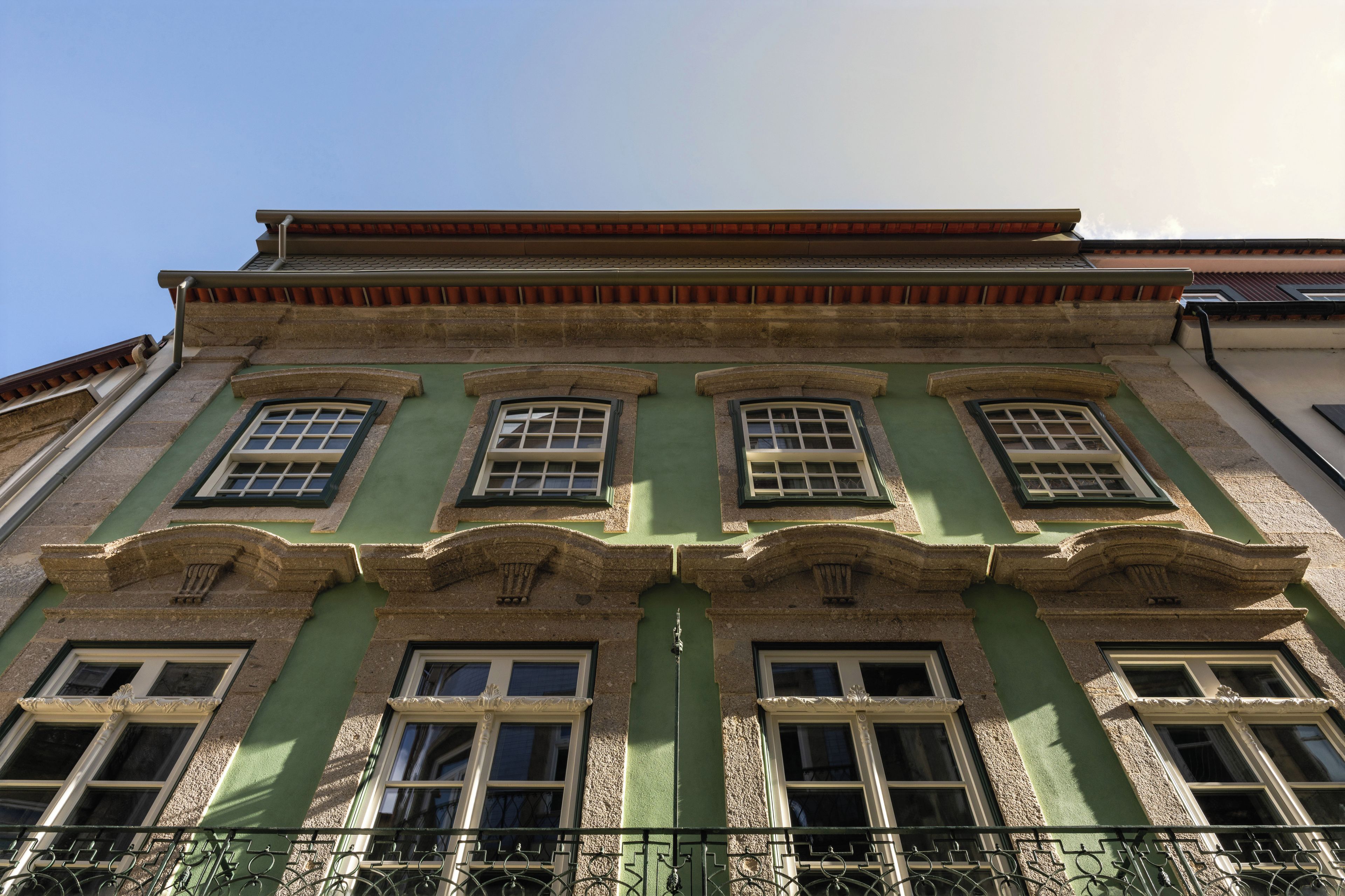 Ein Gebäude mit vielen Fenstern und einer grünen Fassade.