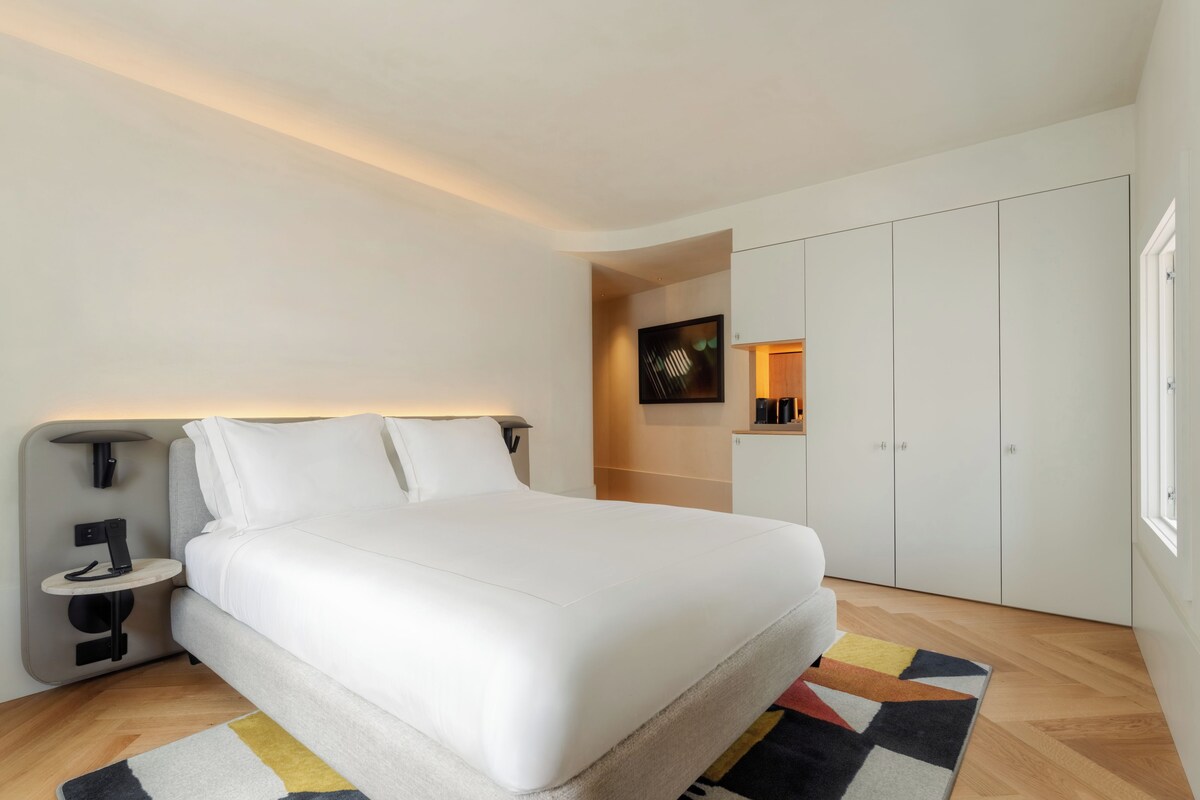 Ein modernes Schlafzimmer mit Bett, Nachttischen, einem Kleiderschrank und einem Beistelltisch.