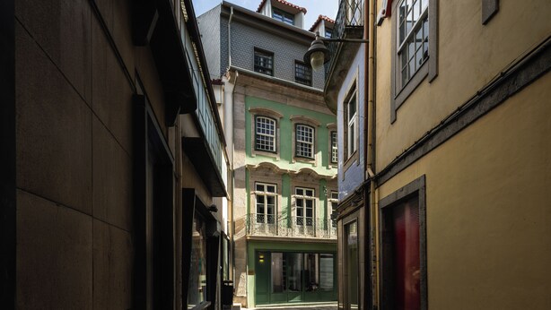 Eine schmale Straße mit Gebäuden an beiden Seiten, mit Balkonen und einer Mischung aus Baustilen.