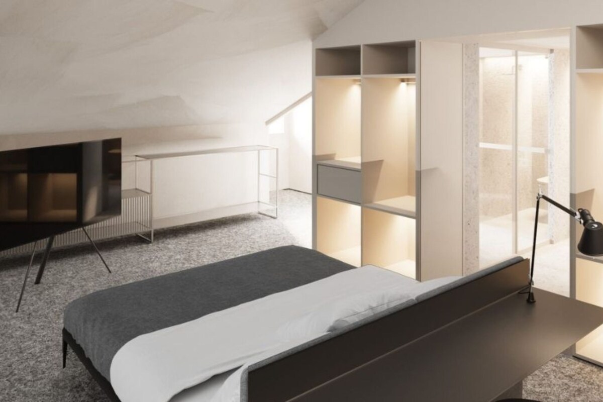 A modern bedroom with a bed, a TV, built-in storage, and a desk.