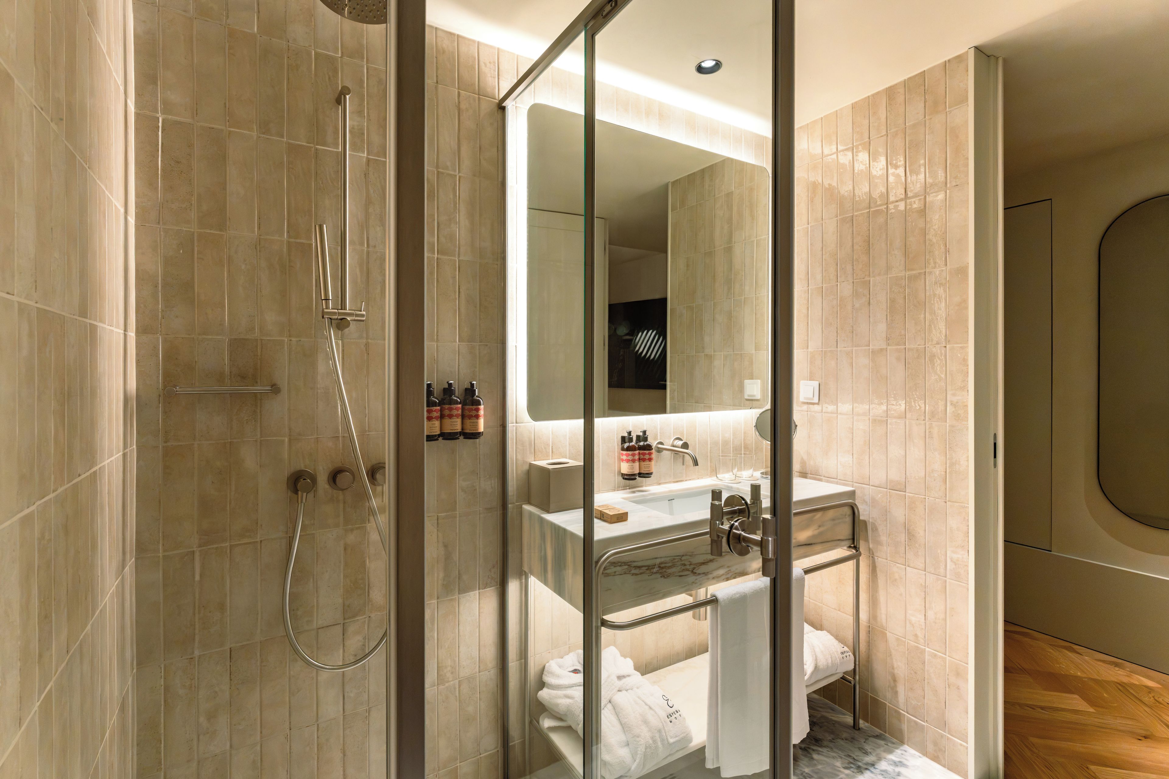 A modern bathroom with a glass shower enclosure, a sink with a marble countertop, and a large mirror.