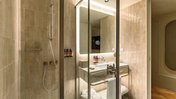 A modern bathroom with a glass shower enclosure, a sink with a marble countertop, and a large mirror.
