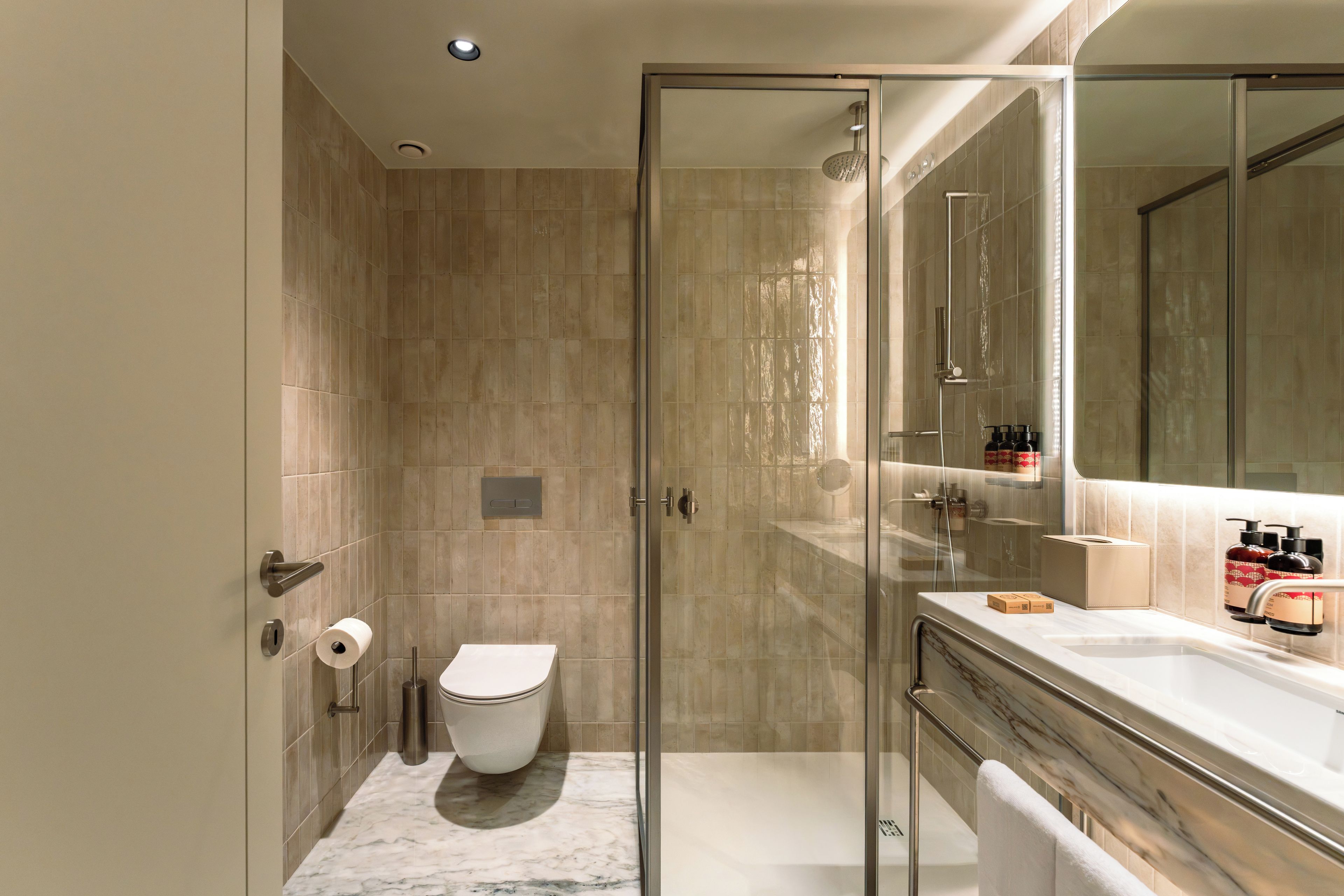 A modern bathroom with a glass shower enclosure, a toilet, and a vanity with a mirror.