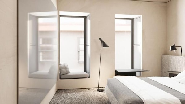 A modern hotel room with a bed, bedside tables, a reading lamp, and a window seat with a view.