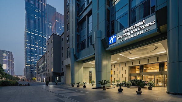 A modern hotel entrance with a prominent sign, large columns, and potted plants. - Holiday Inn Express Beijing Guomao CBD By IHG (Beijing)