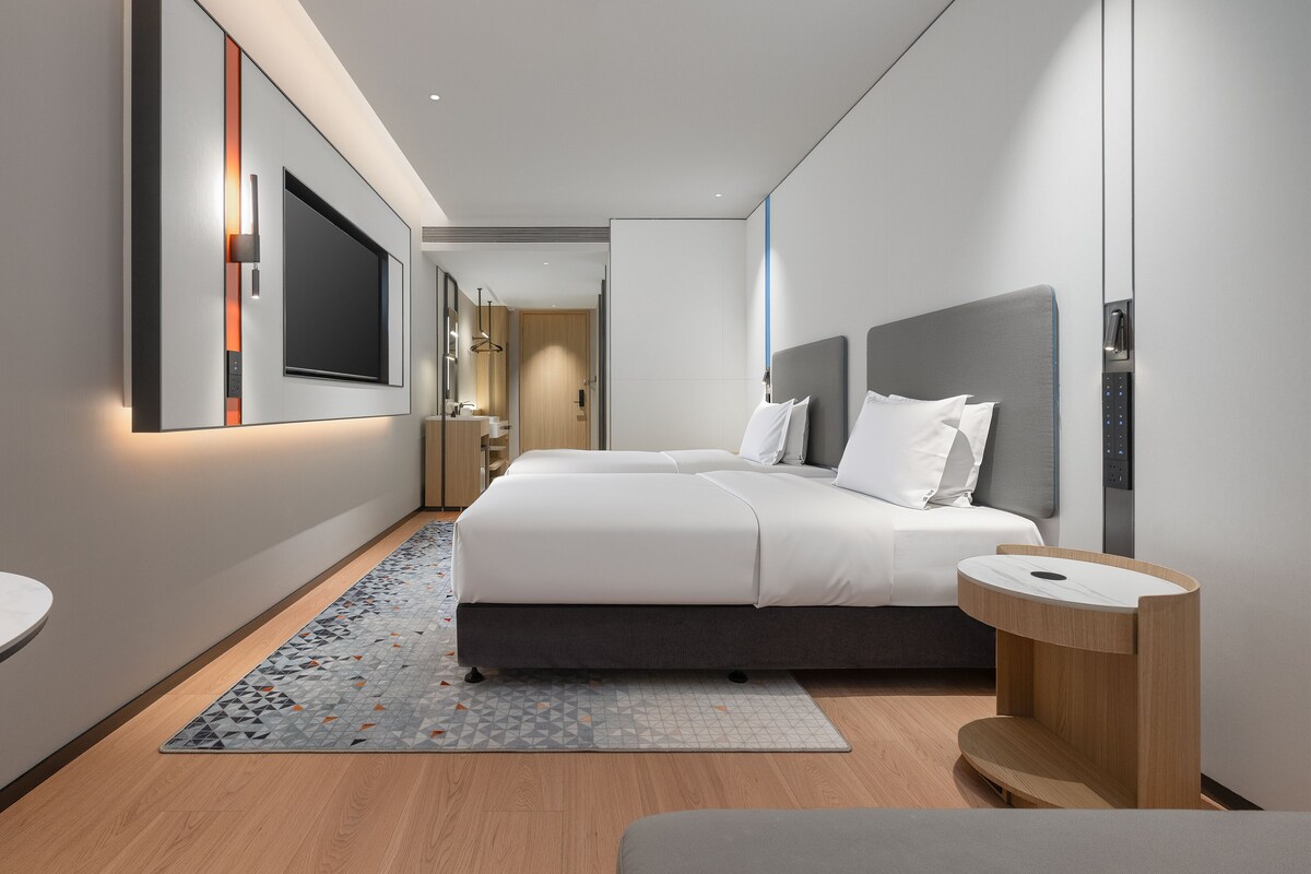A modern hotel room with a large bed, bedside tables, a desk, and a bathroom.