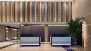 A modern lobby with a high ceiling, vertical wooden slats, and two reception desks with illuminated panels. - Holiday Inn Express Beijing Guomao CBD By IHG (Beijing)