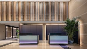 A modern lobby with a high ceiling, vertical wooden slats, and two reception desks with illuminated panels. - Holiday Inn Express Beijing Guomao CBD By IHG (Beijing)