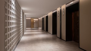 A hallway with a patterned wall, a tiled floor, and a series of doors. - Holiday Inn Express Beijing Guomao CBD By IHG (Beijing)
