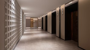 A hallway with a patterned wall, a tiled floor, and a series of doors. - Holiday Inn Express Beijing Guomao CBD By IHG (Beijing)